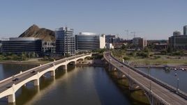 5.7K aerial stock footage fly away from waterfront office buildings and descend between bridges in Tempe, Arizona Aerial Stock Footage | DX0002_142_011
