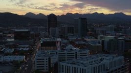 5.7K aerial stock footage a reverse view of office towers at sunset with mountains in background, Downtown Tucson, Arizona Aerial Stock Footage | DX0002_147_014