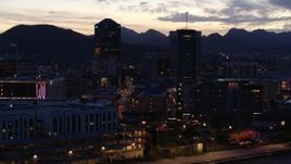 5.7K aerial stock footage reverse view of tall office towers at sunset, mountain range in background, Downtown Tucson, Arizona Aerial Stock Footage | DX0002_147_029