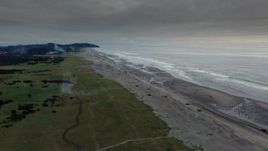 4K aerial stock footage reverse view of the beach as fireworks go off at sunset in Long Beach, Washington Aerial Stock Footage | DX0002_148_038