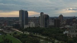 5.7K aerial stock footage view of tall skyscrapers in the city's skyline seen while descending to green park at sunset, Downtown Milwaukee, Wisconsin Aerial Stock Footage | DX0002_155_014