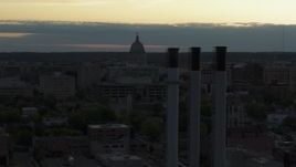 5.7K aerial stock footage focus on the capitol dome at sunset, reveal and fly away from smoke stacks, Madison, Wisconsin Aerial Stock Footage | DX0002_162_003