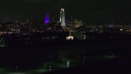 5.7K aerial stock footage of tall skyscrapers behind the fountain lit up at night, Downtown Omaha, Nebraska Aerial Stock Footage | DX0002_173_052