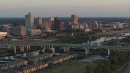 5.7K aerial stock footage of flying by the city's skyline behind the bridge and the river at sunset, Downtown Memphis, Tennessee Aerial Stock Footage | DX0002_181_011