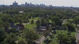 5.7K aerial stock footage of circling the Heidelberg Project outdoor art display and urban homes, reveal the skyline in Detroit, Michigan Aerial Stock Footage | DX0002_195_009
