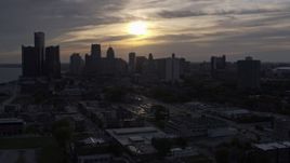 5.7K aerial stock footage of the setting sun behind clouds above the Downtown Detroit skyline, Michigan Aerial Stock Footage | DX0002_197_001