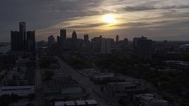 5.7K aerial stock footage of flying by the setting sun behind clouds above the Downtown Detroit skyline, Michigan Aerial Stock Footage | DX0002_197_002
