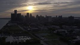 5.7K aerial stock footage of passing by the setting sun behind clouds above the Downtown Detroit skyline, Michigan Aerial Stock Footage | DX0002_197_003