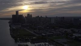 5.7K aerial stock footage ascend and flyby the setting sun behind clouds above the Downtown Detroit skyline, Michigan Aerial Stock Footage | DX0002_197_004