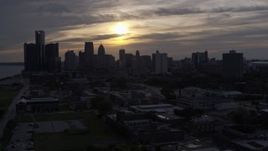 5.7K aerial stock footage of flying by the city's skyline with the setting sun in the clouds above, Downtown Detroit, Michigan Aerial Stock Footage | DX0002_197_006