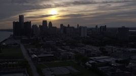 5.7K aerial stock footage of descending past the city's skyline with the setting sun in the clouds above, Downtown Detroit, Michigan Aerial Stock Footage | DX0002_197_007