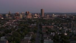 5.7K aerial stock footage of Seneca One Tower and the city's skyline while passing homes at twilight, Downtown Buffalo, New York Aerial Stock Footage | DX0002_204_035