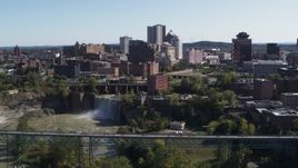 5.7K aerial stock footage focus on the city's skyline behind waterfalls and river during descent, Downtown Rochester, New York Aerial Stock Footage | DX0002_206_030
