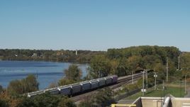 5.7K aerial stock footage of descend by the lake to reveal tracks and a train in Syracuse, New York Aerial Stock Footage | DX0002_211_041