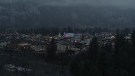 5.7K aerial stock footage ascend from trees to reveal a small town decorated with Christmas trees and lights, Leavenworth, Washington Aerial Stock Footage | DX0002_227_050
