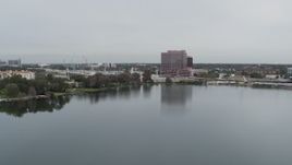 5.7K aerial stock footage descend by lake while focused on office building by light freeway traffic, Orlando, Florida Aerial Stock Footage | DX0003_233_029