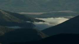 HD stock footage aerial video of fog and evergreens on mountains, zoom to reveal taller Rocky Mountains at sunrise, Colorado Aerial Stock Footage | HDA13_438_01