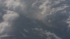 4K stock footage aerial video of reverse view of misty clouds rolling over the snowy Sierra Nevada Mountains, California Aerial Stock Footage | WA002_058