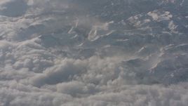 4K stock footage aerial video fly away from snowy mountains and tilt to dense clouds below in the Sierra Nevada Mountains, California Aerial Stock Footage | WA002_062