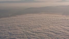 4K stock footage aerial video approach mountains at sunset, and tilt to clouds below in Southern California Aerial Stock Footage | WA005_012