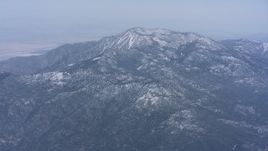 4K stock footage aerial video of a reverse view of snow-capped mountains, tilt to reveal a peak in Southern California Aerial Stock Footage | WA007_029
