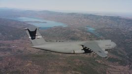 4K stock footage aerial video of a Lockheed C-5 flying over mountains near a lake, Northern California Aerial Stock Footage | WAAF01_C074_0117TM