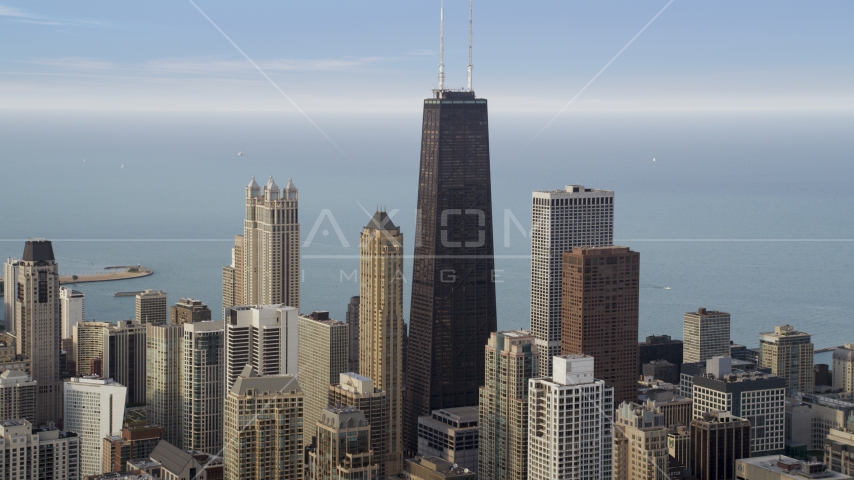 John Hancock Center towering over neighboring skyscrapers in Downtown Chicago on a hazy day, Illinois Aerial Stock Photo AX0001_054.0000163F | Axiom Images