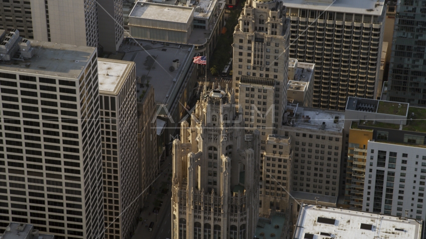 A flag flying at top of Tribune Tower in Downtown Chicago, Illinois Aerial Stock Photo AX0001_118.0000208F | Axiom Images