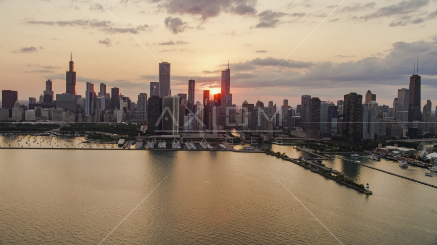 The setting sun behind the Downtown Chicago skyline, seen from Lake Michigan on a cloudy day, Illinois Aerial Stock Photo AX0003_033.0000157F | Axiom Images