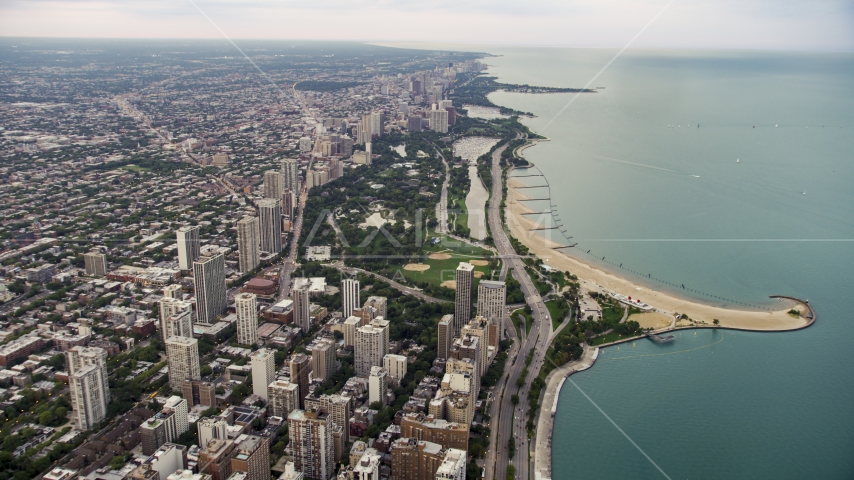 Lake Shore Drive by apartment buildings and Lincoln Park on a cloudy day at sunset, North Chicago, Illinois Aerial Stock Photo AX0003_053.0000251F | Axiom Images