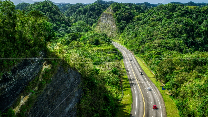 Highway with light traffic through lush green mountains, Karst Forest, Puerto Rico Aerial Stock Photo AX101_079.0000000F | Axiom Images