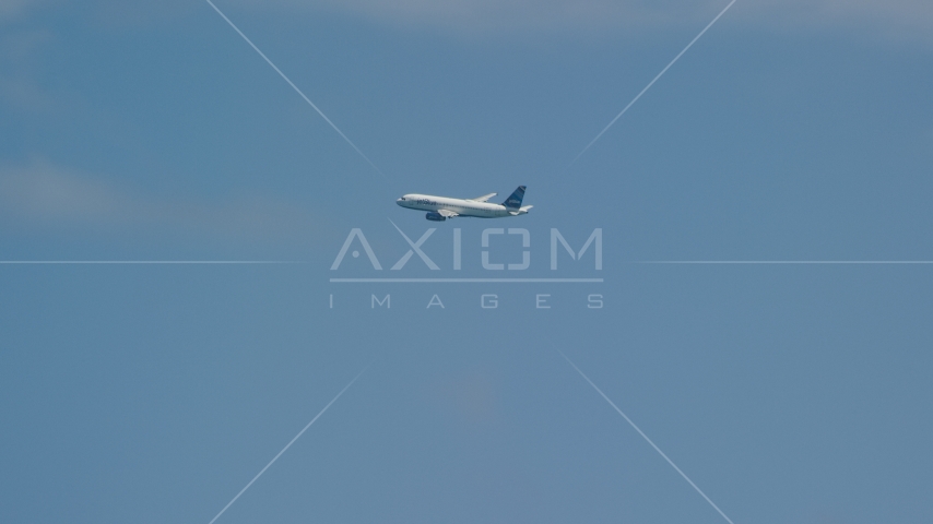 A passenger plane in blue skies over Carolina, Puerto Rico Aerial Stock Photo AX102_014.0000032F | Axiom Images