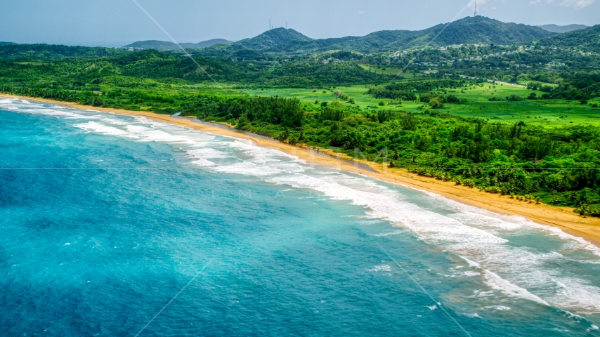 Waves rolling toward an empty beach and jungle in Luquillo, Puerto Rico  Aerial Stock Photo AX102_052.0000138F | Axiom Images