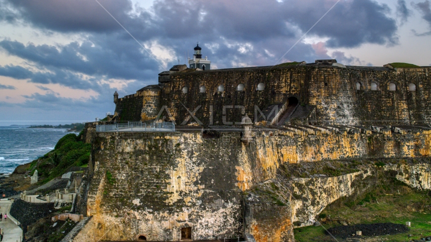 The walls of Fort San Felipe del Morro by Caribbean blue waters, Old San Juan, twilight Aerial Stock Photo AX104_082.0000258F | Axiom Images