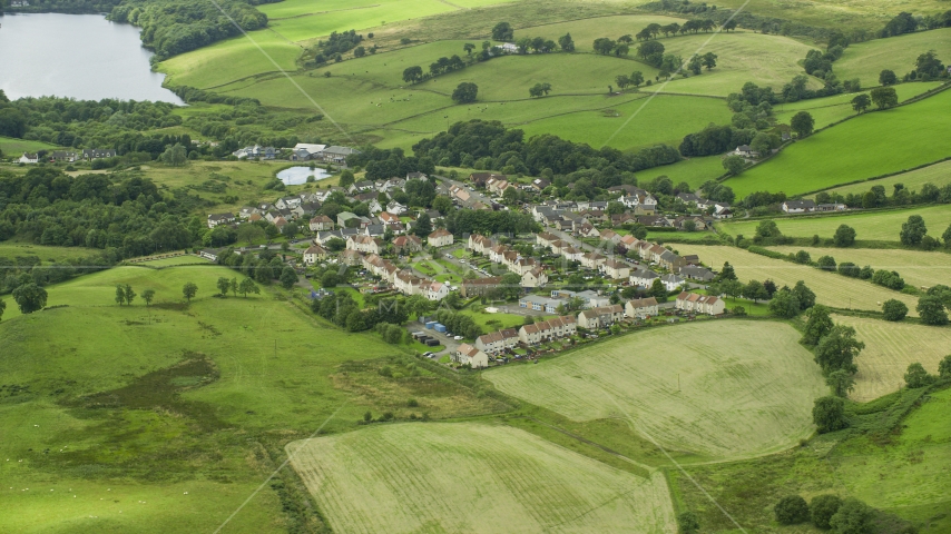 Rural homes surrounded by green fields in the village of Banton, Scotland Aerial Stock Photo AX109_003.0000251F | Axiom Images