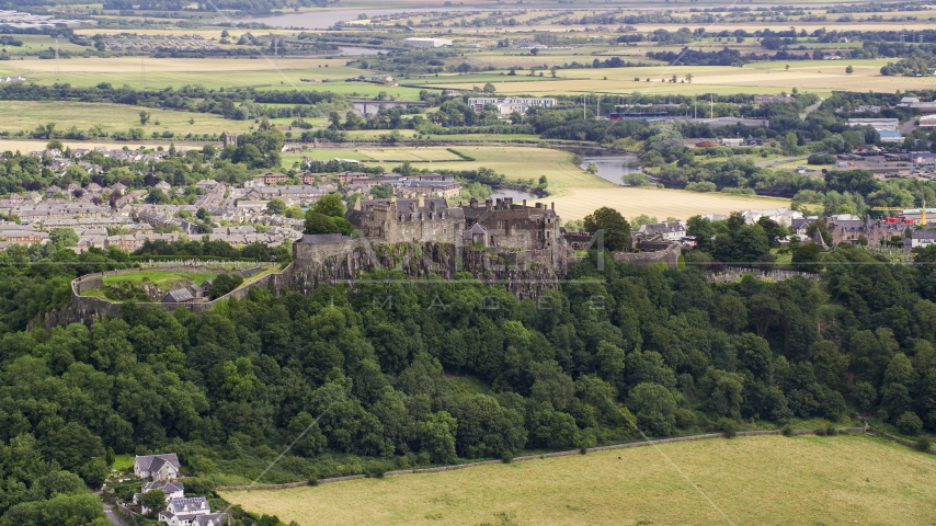 Historic Stirling Castle atop a tree-covered hill in Scotland Aerial Stock Photo AX109_020.0000000F | Axiom Images