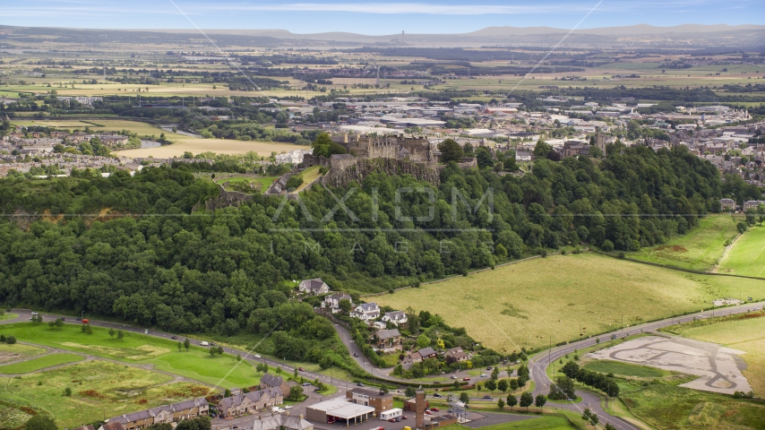 Iconic Stirling Castle among tree covered hillside, Scotland Aerial Stock Photo AX109_022.0000000F | Axiom Images