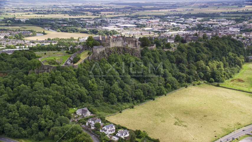 Stirling Castle on a tree covered hillside, Scotland Aerial Stock Photo AX109_023.0000158F | Axiom Images
