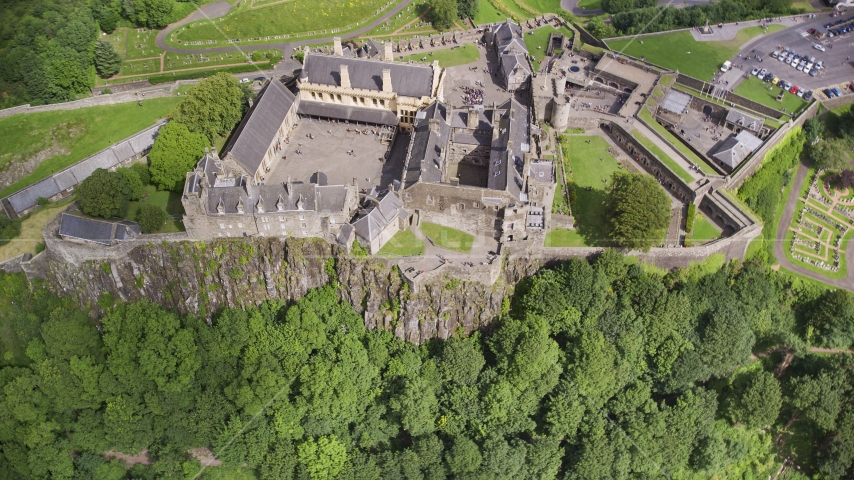 Iconic Stirling Castle and a tree covered hillside, Scotland Aerial Stock Photo AX109_043.0000155F | Axiom Images