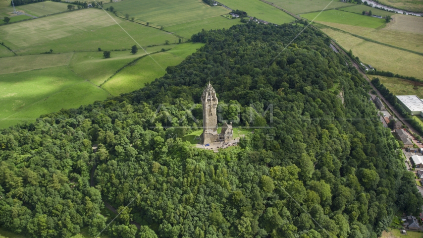The historic Wallace Monument surrounded by trees on Abbey Craig hill in Stirling, Scotland Aerial Stock Photo AX109_100.0000008F | Axiom Images