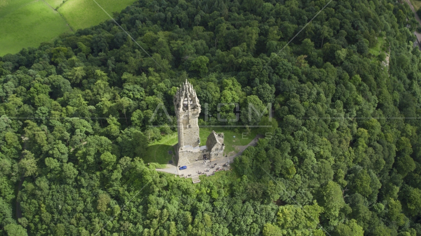 The iconic Wallace Monument surrounded by trees on Abbey Craig, Scotland Aerial Stock Photo AX109_100.0000080F | Axiom Images
