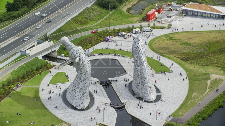 The back of the iconic Kelpies sculptures in Falkirk, Scotland Aerial Stock Photo AX109_125.0000127F | Axiom Images