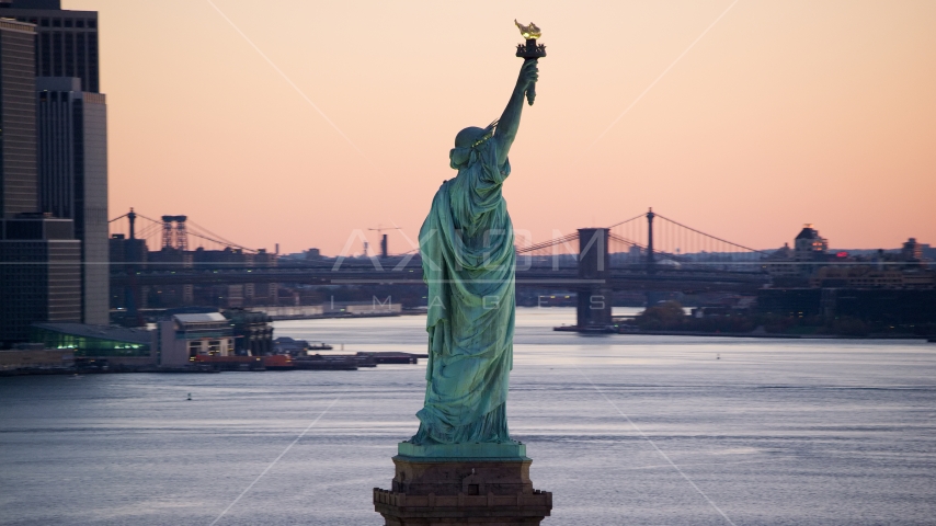 Statue of Liberty at sunrise, Brooklyn Bridge in the background, New York Aerial Stock Photo AX118_044.0000159F | Axiom Images