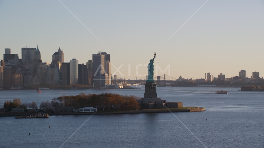 Statue of Liberty and Lower Manhattan skyscrapers at sunrise in New York City Aerial Stock Photo AX118_132.0000000F | Axiom Images