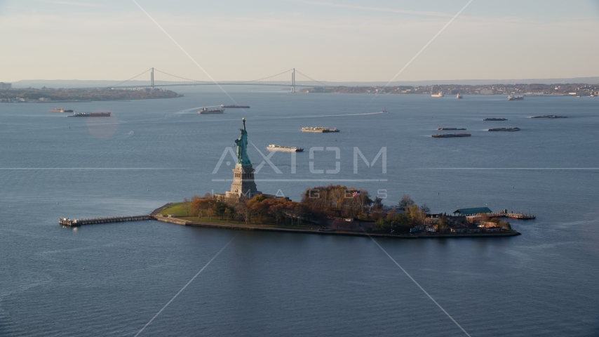 Statue of Liberty and barges in New York Bay at sunrise in New York Aerial Stock Photo AX118_216.0000172F | Axiom Images