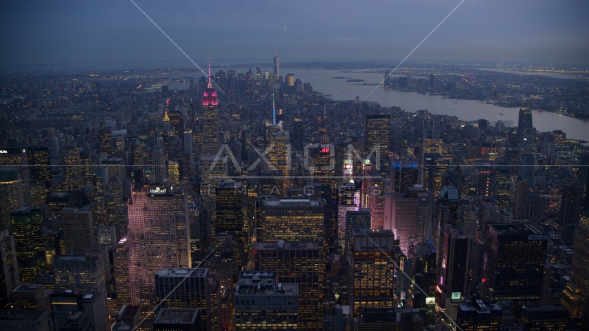 Lights of Times Square and Midtown skyscrapers, Lower Manhattan towers in distance at sunset, New York City Aerial Stock Photo AX121_103.0000114F | Axiom Images