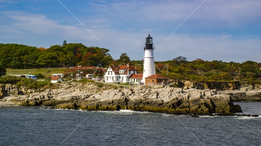 The Portland Head Light on a rocky shore, seen from the ocean in autumn, Cape Elizabeth, Maine Aerial Stock Photo AX147_316.0000190 | Axiom Images