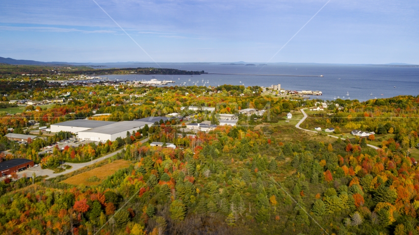 A forest near warehouse buildings and small coastal town, autumn, Rockland, Maine Aerial Stock Photo AX148_076.0000028 | Axiom Images