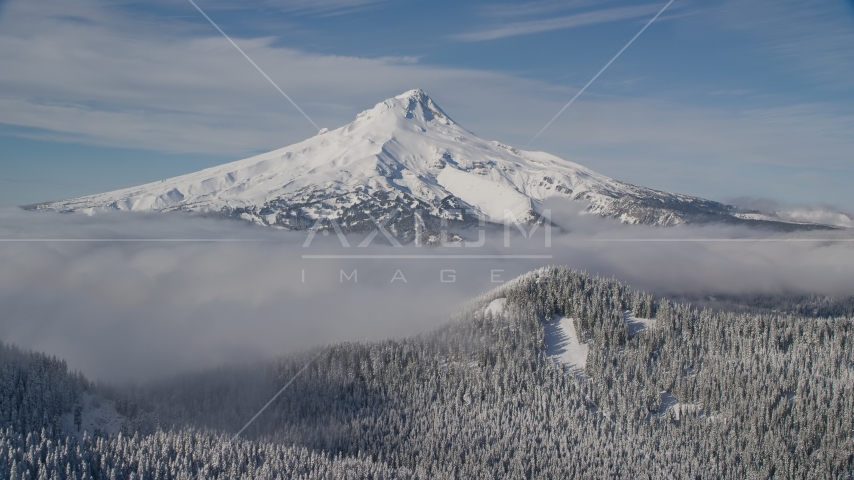 Mount Hood behind low clouds and snowy forest in the Cascade Range, Oregon Aerial Stock Photo AX154_112.0000000F | Axiom Images