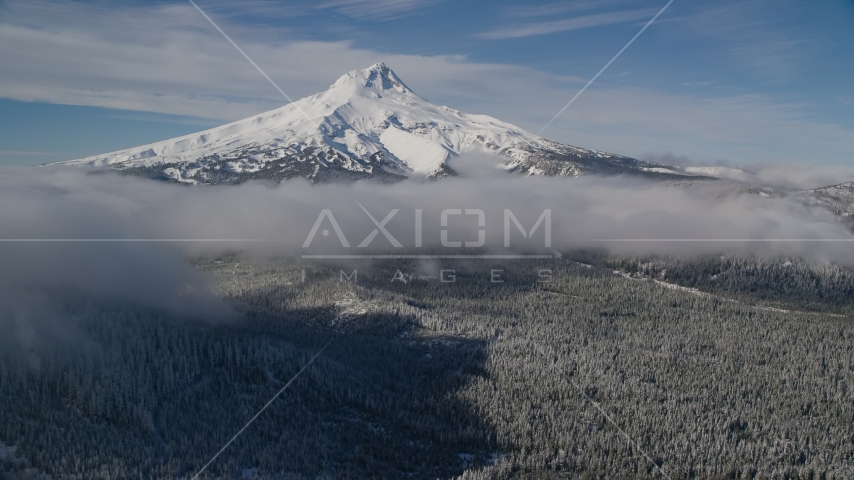 Snowy mountain peak with low clouds over forest, Mount Hood, Cascade Range, Oregon Aerial Stock Photo AX154_118.0000000F | Axiom Images